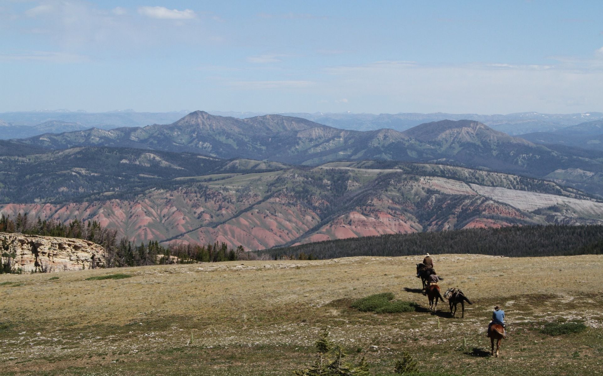 Riders on horseback crossing a meadow below the Absaroka Range in northwest Wyoming